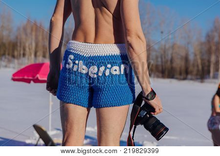 Novokuznetsk, Kemerovo region, Russia - 23 Feb, 2017 : White beaches of Siberia is an enterteiment activity where people playing beach games dressed in bikini in winter. Man in blue shorts with camera