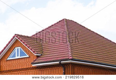 The house with a roof of classic tiles. Roof tiles made of baked clay on the roof.