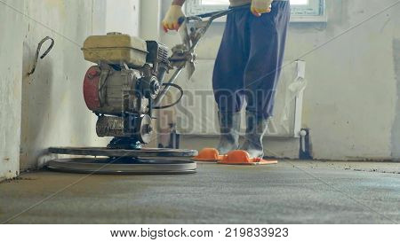 Builder polishing mortar floor at construction site of new appartments. Mechanized grout screed concrete floor close-up