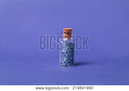 Ultra violet concept: bottle with sparkles on ultra violet background. close up.