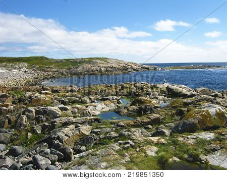 An overview of the White sea coast line. A littoral tide zone with stones and aglae. Blue sky with some clouds.
