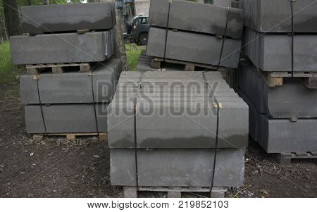 Stack of concrete curbstone. Construction process the dark one
