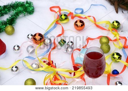 Two glasses of wine and gifts with a red satin ribbon apples pine cones branches gold ornaments garlands