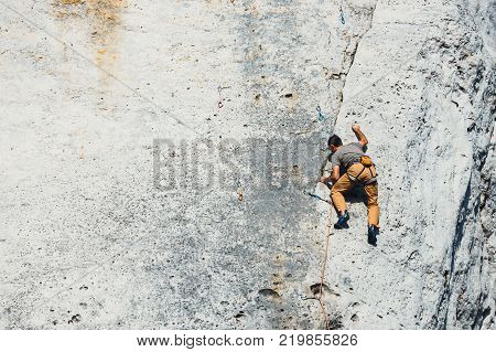 Poland Podlesice - March 04 2017: Side view of adult male rock climber on vertical flat wall with poor relief. Gora Zborow is a very popular destination among climbers
