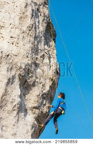 Poland Podlesice - March 04 2017: Side view of adult male rock climber on vertical flat wall with poor relief. Gora Zborow is a very popular destination among climbers
