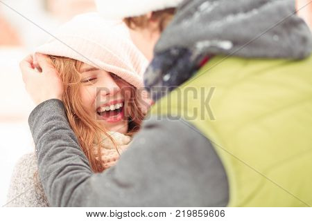 A boy tries to fix a girls hat. They are laughing.
