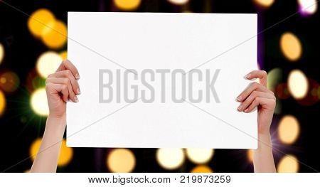 Female hands holding a blank placard with abstract lights bokeh background