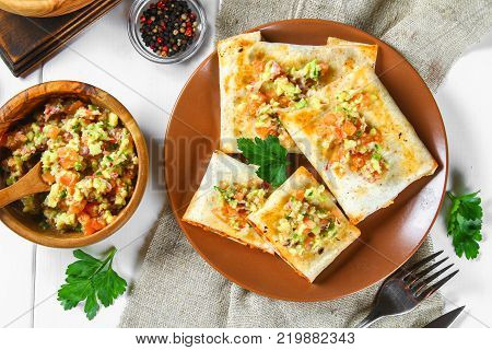 Traditional Mexican dish - chimichanga. Corn cake with minced meat, pepper, onion, garlic, oregano, zira and guacomole sauce from avocado