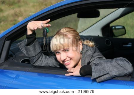 Young Blond Woman In A Blue Car With Key From It