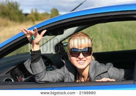 Young Blond Woman In A Blue Car With Key From It