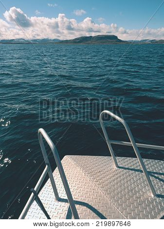 Sea fishing from steel fishing boat on open water. Rocky island et horizon. Cold sunny day on sea