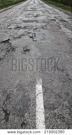 Bad asphalt road with white line.picture was made in Latvia