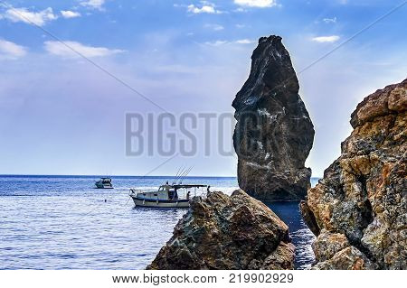 Fishing in the sea off the rocks from the deck of a marine pleasure boats.