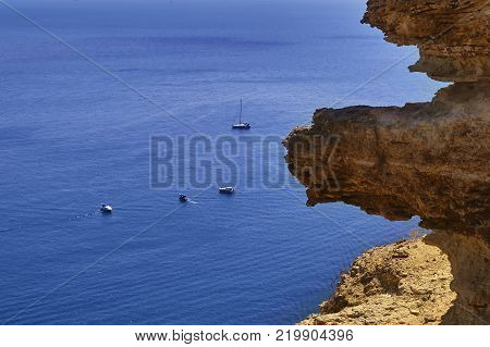 Yellow rocks on blue sea background on a clear sunny summer day.