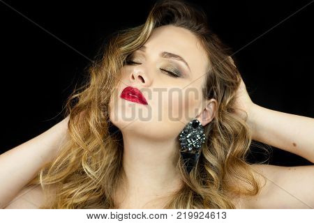 Portrait of a young beautiful woman with red lipstick on a black background. Makeup. Holidays.