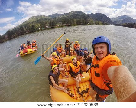 mountain Altai RUSSIA - July 16 2017: man in helmet holds action camera and makes selfie on background of friends with oars rafting