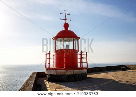Red lighthouse lamp room on blue sky and sea background in Nazare, Portugal