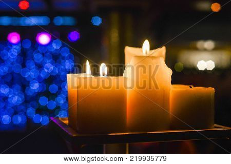 Candles light. Abstract candle background. Golden light of candle flame. Closeup of a red candle with creamy bokeh background.