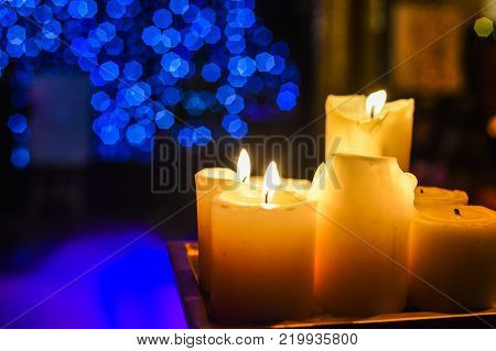 Candles light. Abstract candle background. Golden light of candle flame. Closeup of a red candle with creamy bokeh background.