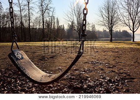 swing set in late fall park with lake