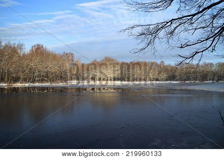 beautiful winter landscape the river is icebound, the trees under the snow are lit by the setting sun