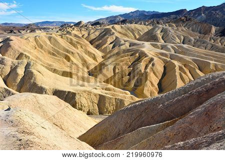 Golden badlands eroded into waves, pleats and gullies at Zabriskie Point in the Death Valley National Park in USA.