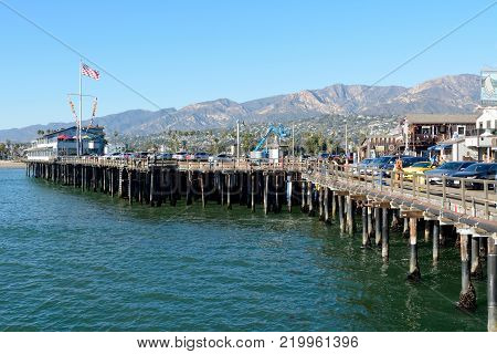 Santa Barbara, California, United States of America - November 30, 2017. Stearns Wharf historic wooden pier in Santa Barbara, CA, with cars, commercial properties and people.