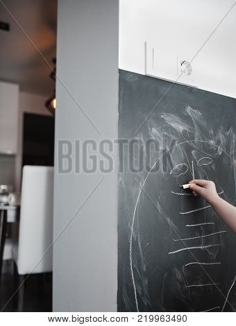 Cute little girl drawing on blackboard. Toddler girl having fun outdoors, holding chalk and drawing.