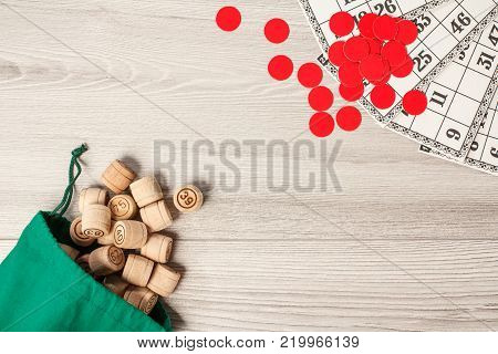 Board game lotto. Wooden lotto barrels with green bag, game cards and red chips for a game in lotto. Top view