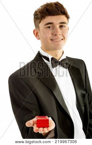 18 year old wearing a tuxedo smiling with a ring box isolated on a white background