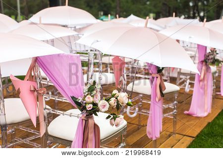 Chairs, flowers and umbrellas at an outdoor ceremony.