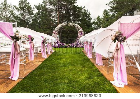 Outdoor wedding ceremony with umbrellas in the forest.