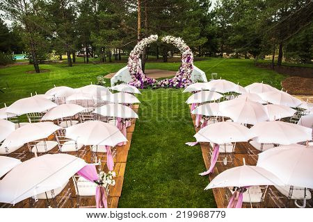 Outdoor wedding ceremony with umbrellas in the forest.