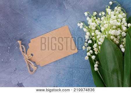 Lilly of the valley flowers on for Mothers Day on gray stone background with copy space on paper note