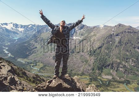 A tourist raised his hands to the sky reveal the joy of conquering the mountain peaks. People tively in the form of standing on the edge of a cliff and enjoy the success