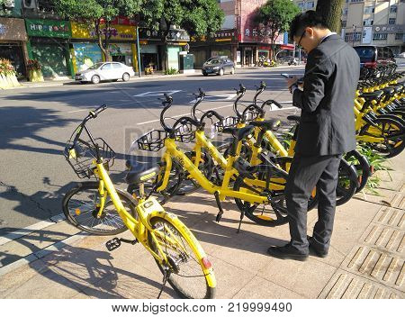 ZHONGSHAN;GUANGDONG;China-December 1;2017:office gentleman prepaing to ride a shared bike.Bicycle-sharing is very popular in China.