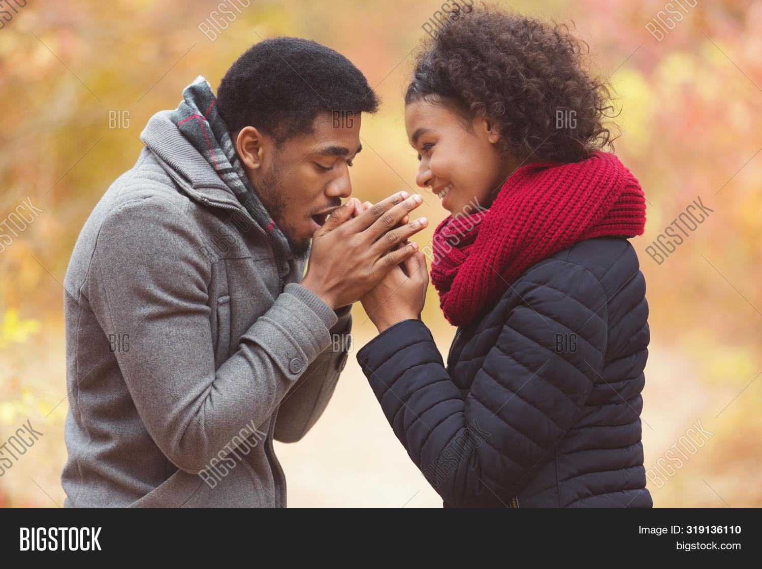 замерзшая девушка. люди зимой. поцелуй в ладонь. мужчина греет руки. девушка греет руки дыханием.