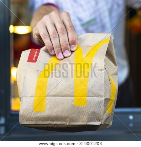 Sankt-petersburg/russia - July 21 2019: Mcdonalds Worker Holding Bag Of Fast Food. Hand With A Paper