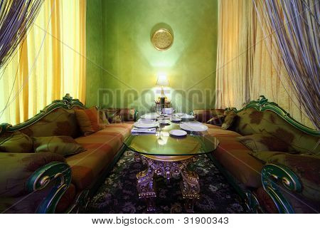 glasbord med servering, lampe og udskårne sofaer i østlige luksus restaurant