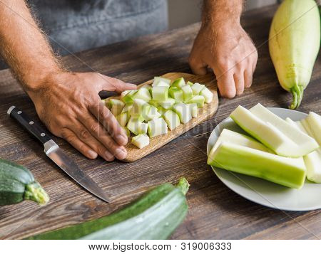 Zucchini Harvest. Man Slices Zucchini Cubes For Freezing On Wooden Table. Farm Organic Zucchini Harv