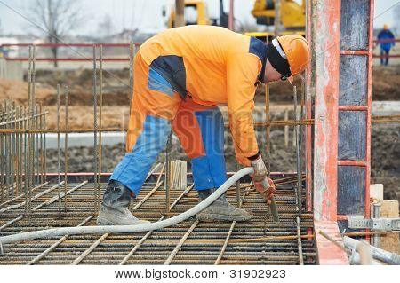 budowniczy pracownika z kompaktowanie maszyna wibrator wlewa Beton szalunki zbrojenia