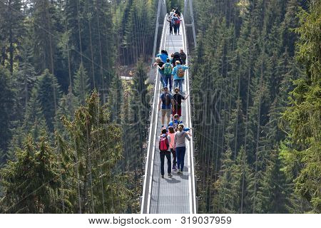 Bad Wildbad, Germany - April 22, 2019: Tourists Walk Along A Long And Suspended Iron Cable Bridge Fo