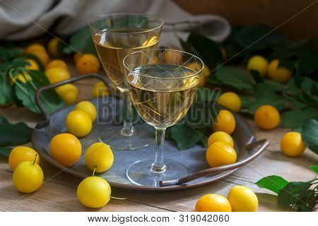 Cherry Plum Liqueur In Small Glasses And Cherry Plum On A Wooden Background. Rustic Style.