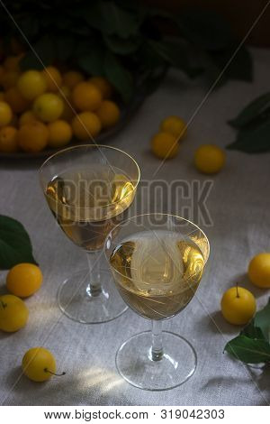Cherry Plum Liqueur In Small Glasses And Cherry Plum On A Wooden Background. Rustic Style.