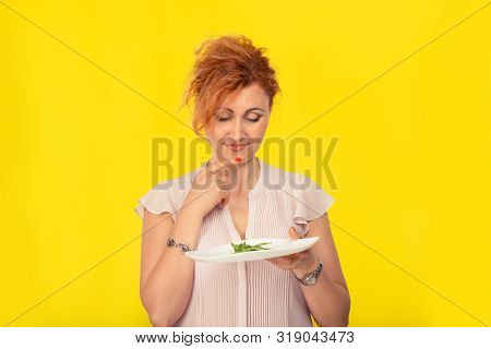 Smiling Woman Holding A Plate With A Small Portion Of Green Rocket Salad On It, Looking At It Smilin