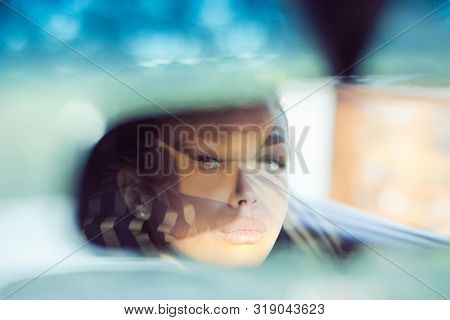 Beautiful Woman Driver Reflecting In The Rear View Mirror. Driving Her Car Concept. Artistic Shot Wi