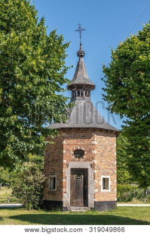 Bokrijk, Belgium - June 27, 2019: Red Brick Octagonal Chapel Of Metsteren With Dark Gray Roof And Cr