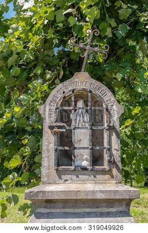 Bokrijk, Belgium - June 27, 2019: Closeup Of Small Gray Stone Chapel Niche Along Road With White Sta