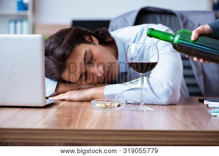 Male employee drinking alcohol and smoking cigarettes at workpla