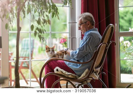 Senior man sitting in a rocking chair with his cat in his lap
